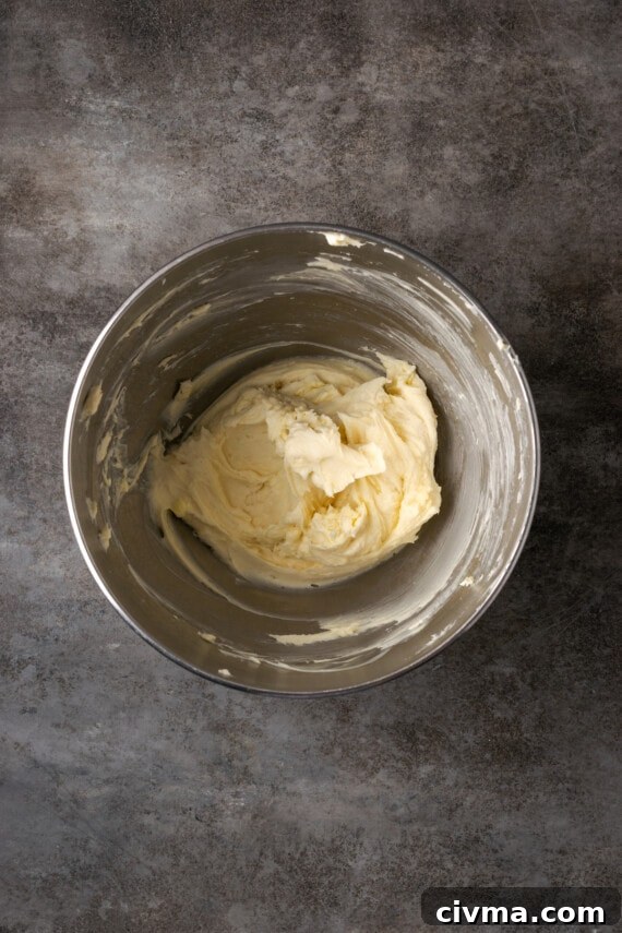 Cream cheese, butter, and sugar creamed together in a metal mixing bowl.
