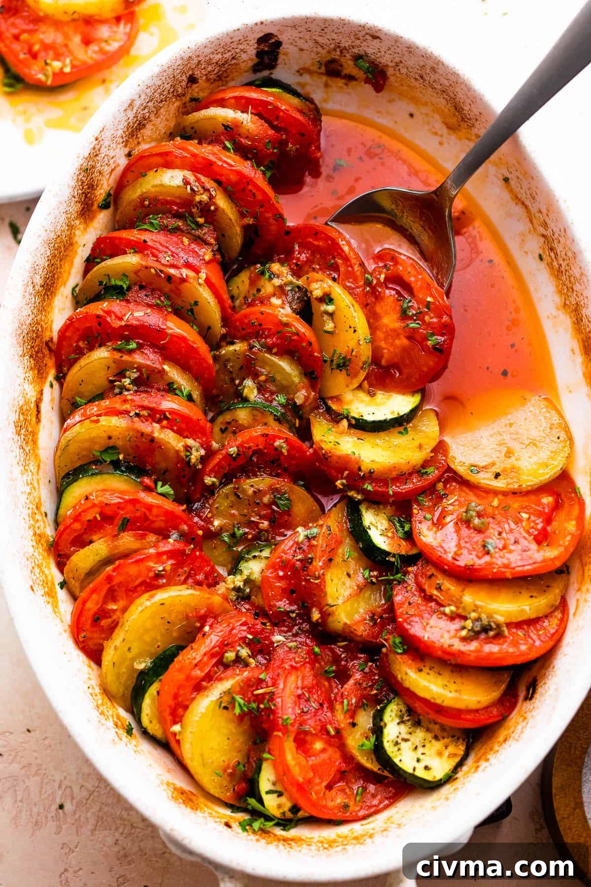 overhead shot of zucchini, tomato, and potato slices arranged accordion style in a baking dish.