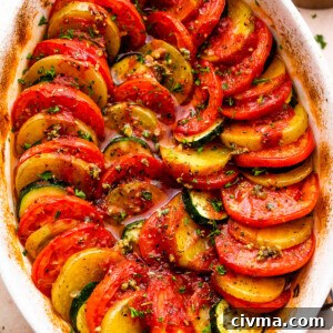 overhead shot of zucchini, tomato, and potato slices arranged accordion style in a baking dish.