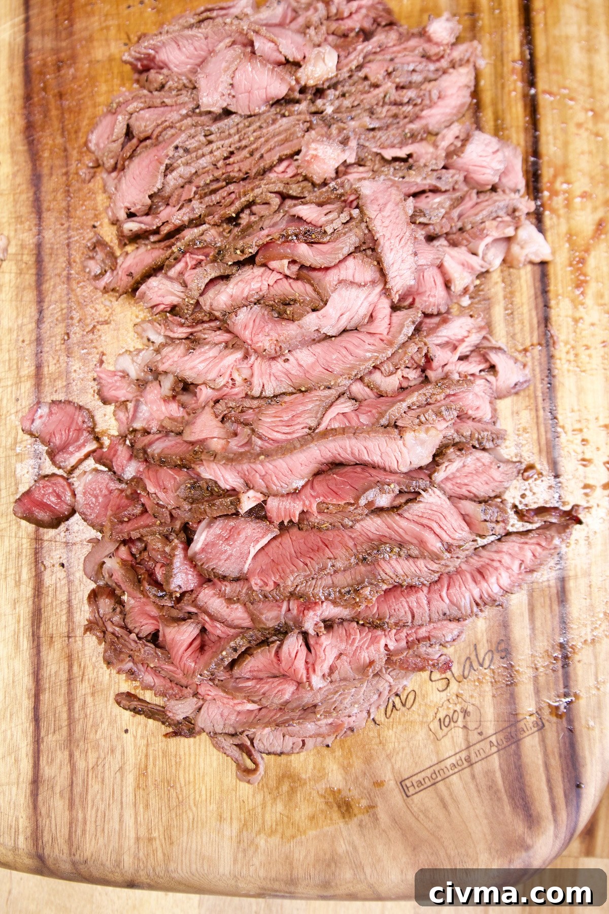 Philly cheesesteak sandwiches. Sliced sirloin steak on a cutting board.