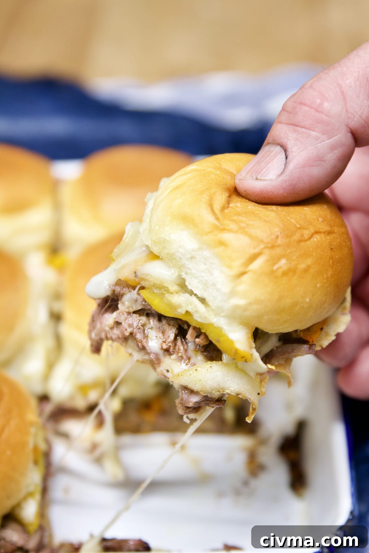 Philly Cheesesteak Sliders with provolone. Pulling slider sandwich from the pan.