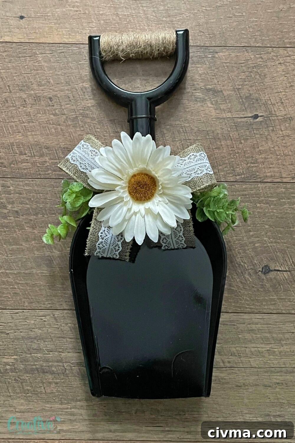 Rustic farmhouse door wreath made from a painted plastic shovel with greenery and a burlap bow