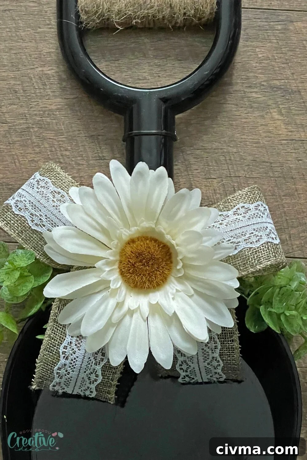 Close-up of a farmhouse wreath with burlap ribbon, greenery, and white flowers