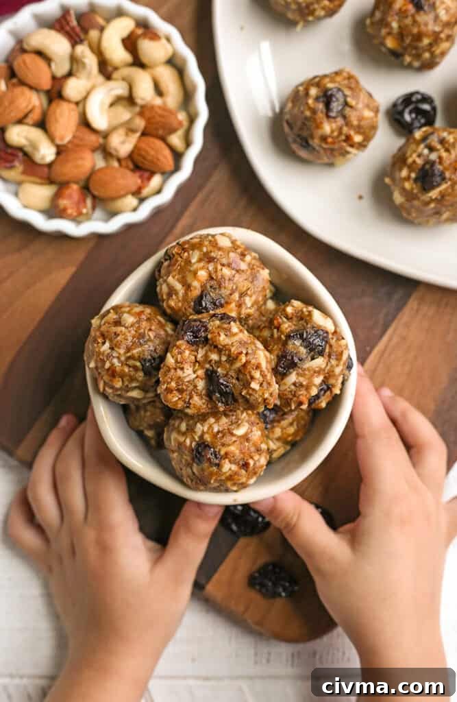 granola bites in a small bowl with two small hands holding it