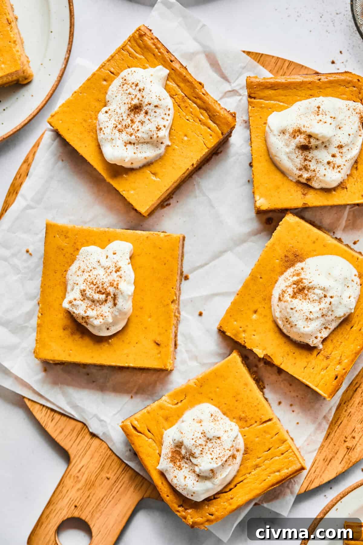 pumpkin pie cheesecake bars on a cutting board with parchment paper
