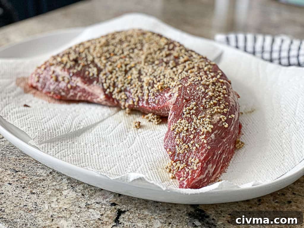 How to Smoke Meat at Home: A Beginner's Guide 6 Side shot of Tri Tip Steak with garlic on a plate.