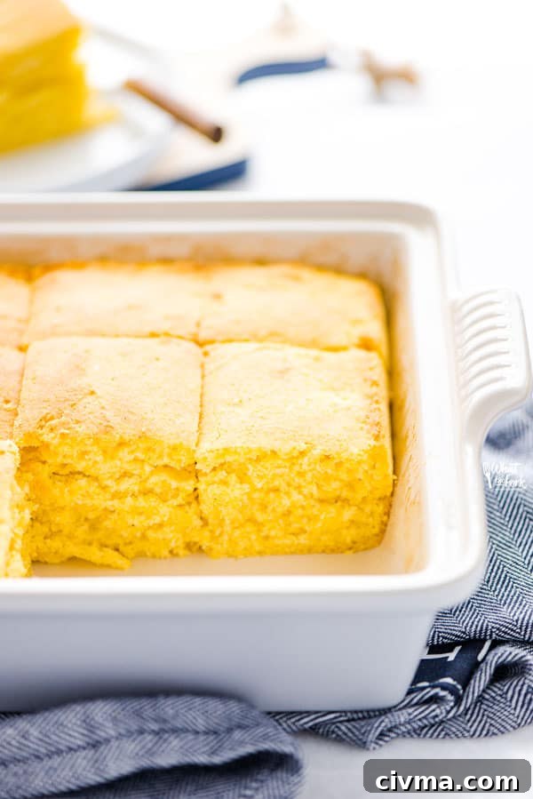 Baked and sliced gluten free sourdough cornbread recipe still in a gray stoneware pan on top of a blue kitchen towel