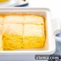 Baked and sliced gluten free sourdough cornbread recipe still in a gray stoneware pan on top of a blue kitchen towel