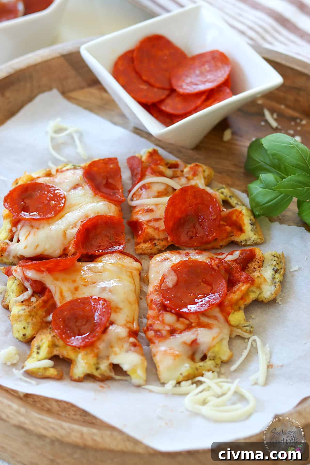 A cooked chaffle pizza on parchment paper with pepperoni slices and basil.