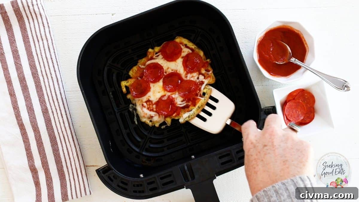 Removed a cooked pizza chaffle from an air fryer basket.