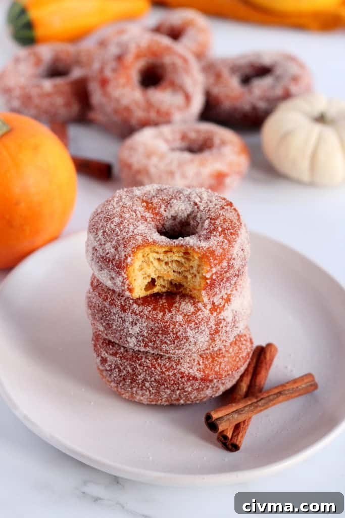 three donuts piled on each other with other donuts in background