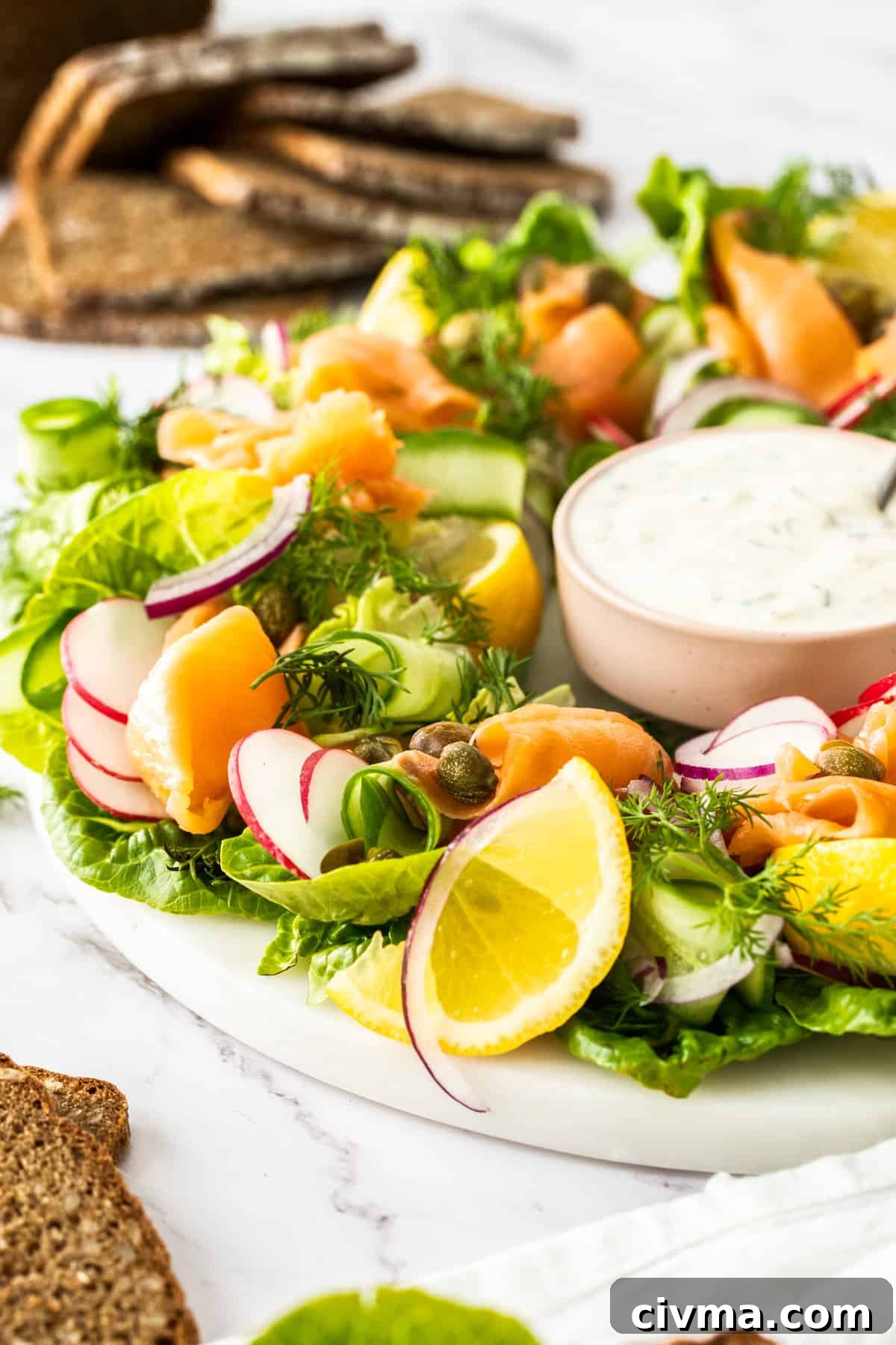 Side angle of the smoked salmon wreath with a bowl of dressing in the centre of the wreath.