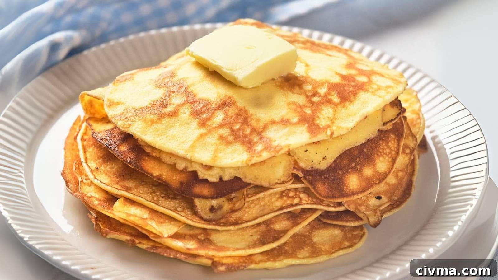 A stack of golden pancakes topped with a square of butter on a white plate.