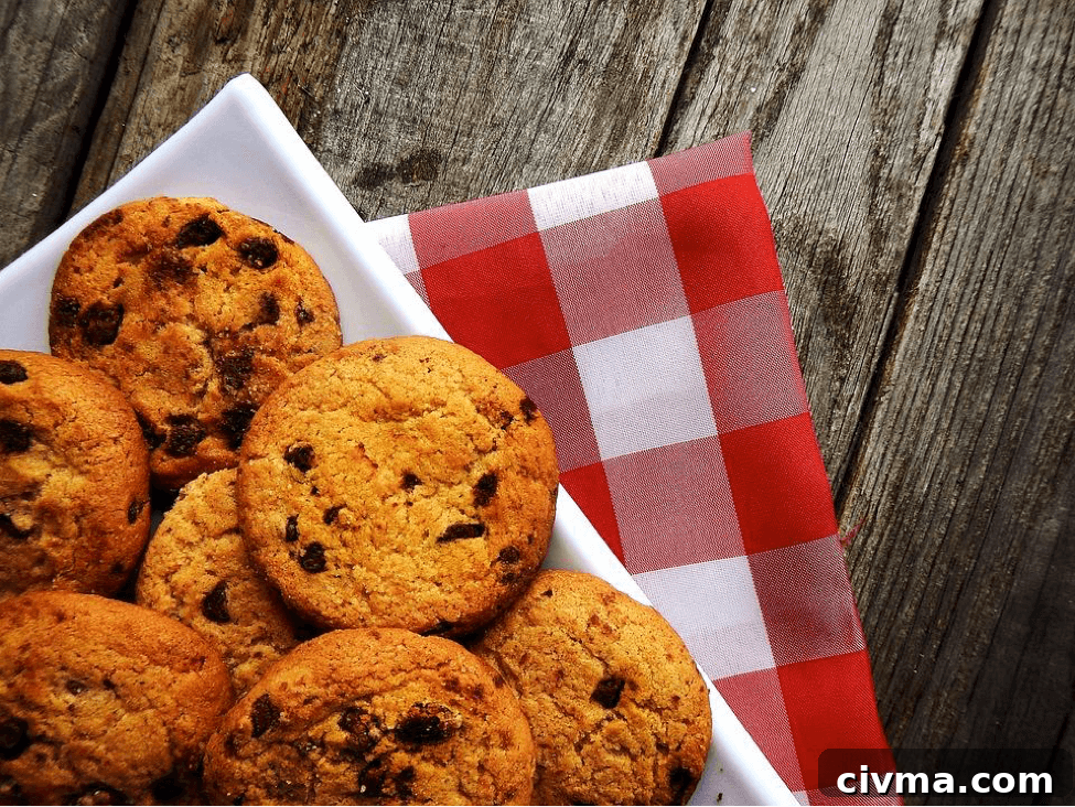Corner angle of a white plate of Oatmeal Chocolate Chip Cookies over a red checked napkin sitting on a wooden board.